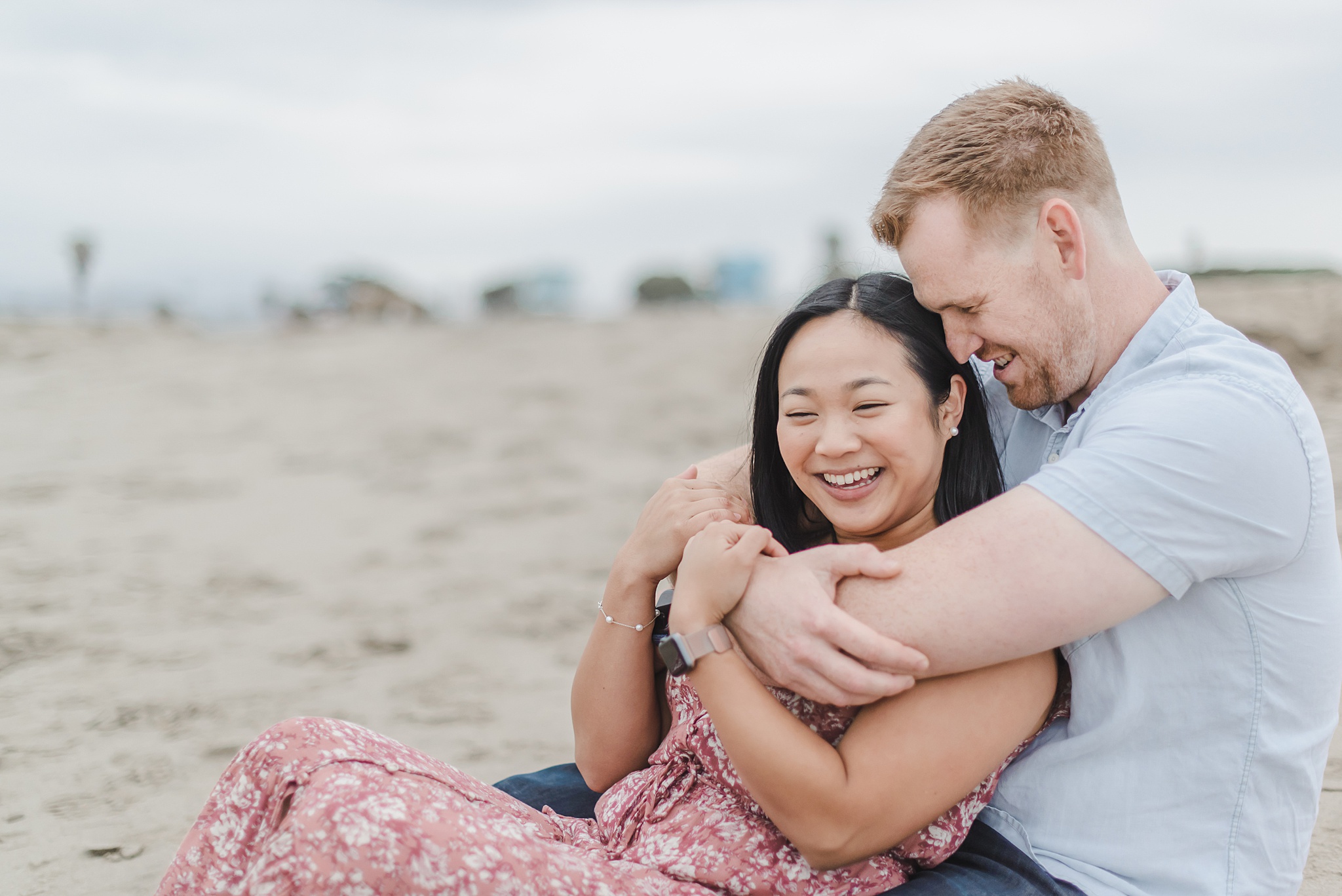 couple sitting in the sand holding each other at the beach