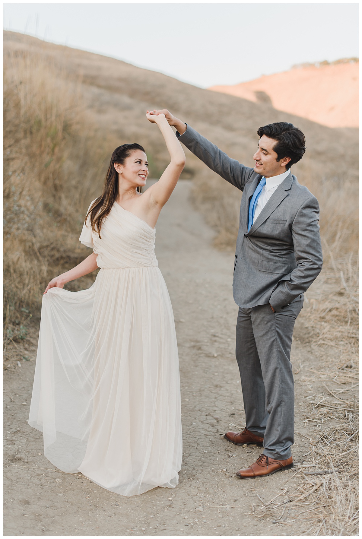 husband twirling wife while she holds the side of her dress