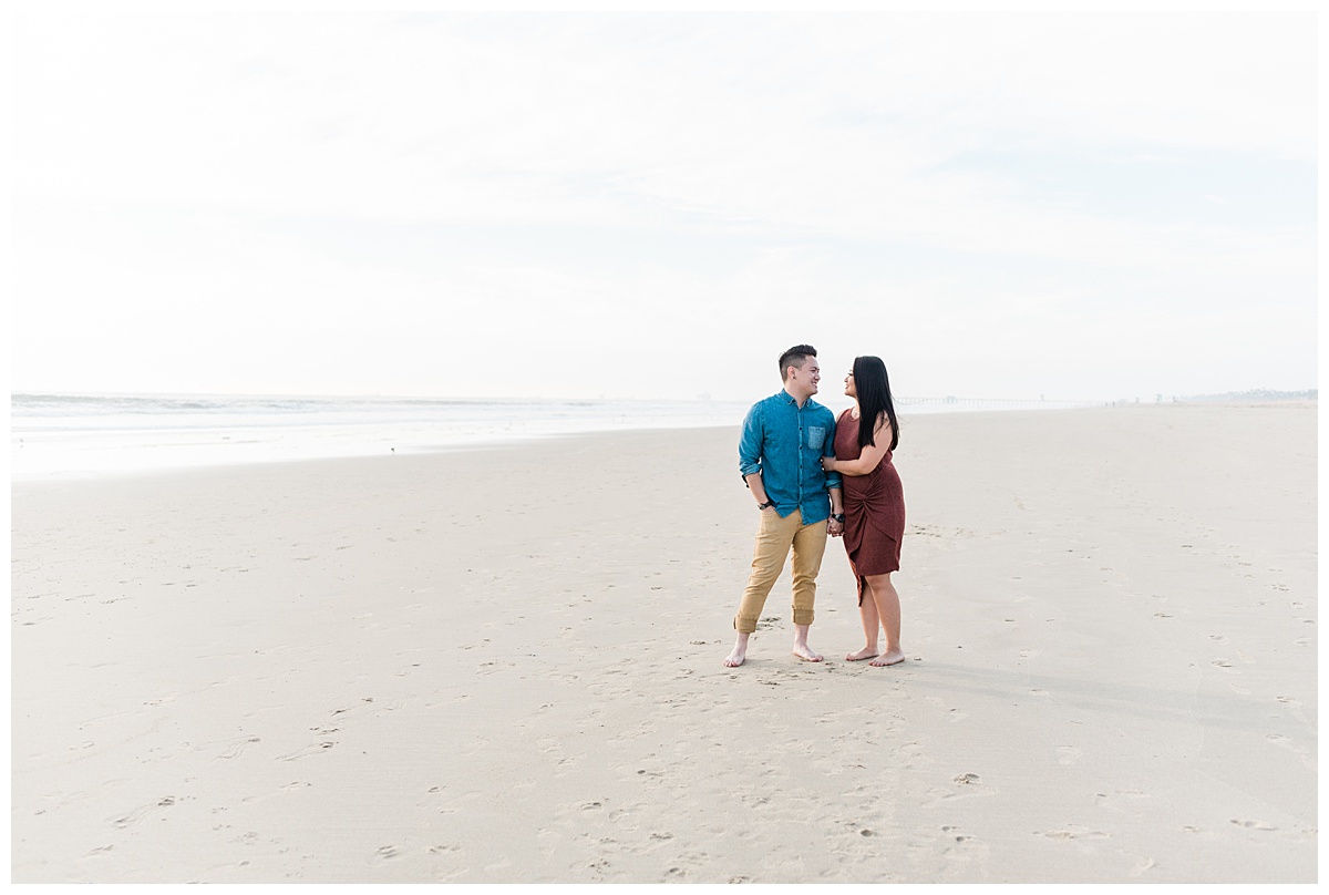 engaged couple standing on Huntington Beach