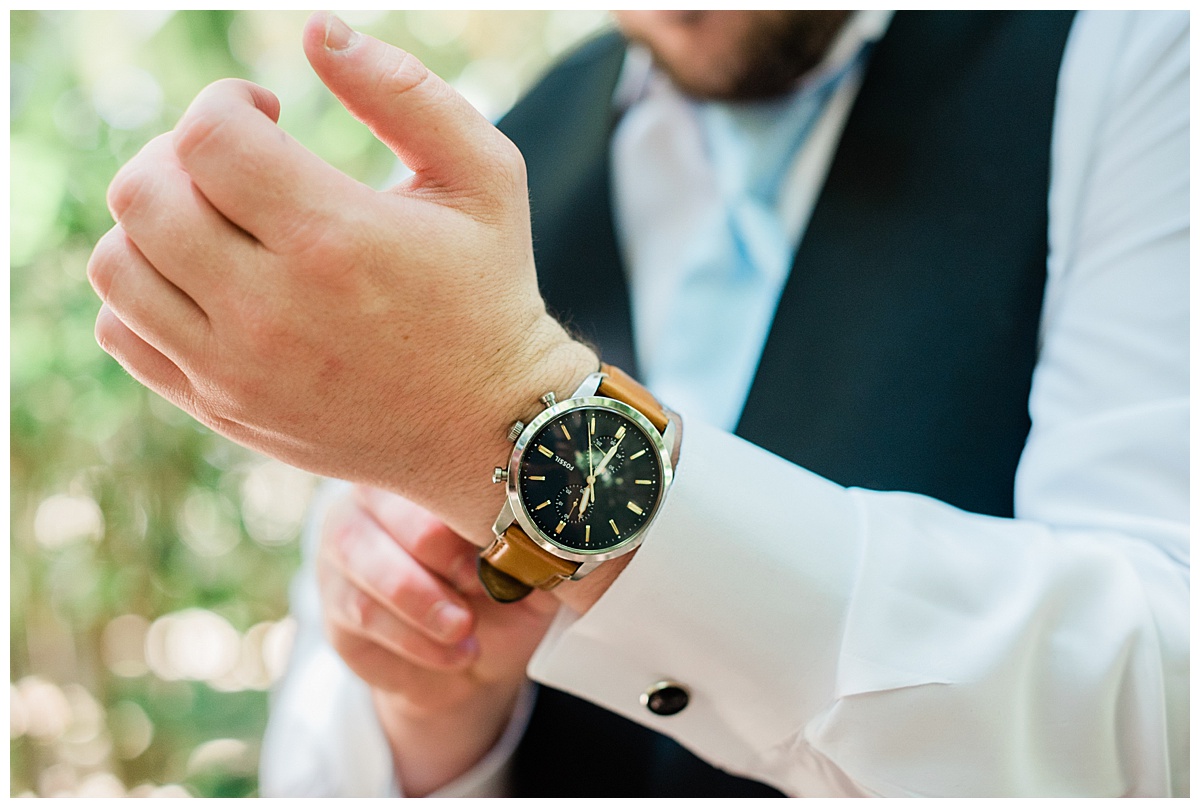 close up of groom fixing his watch