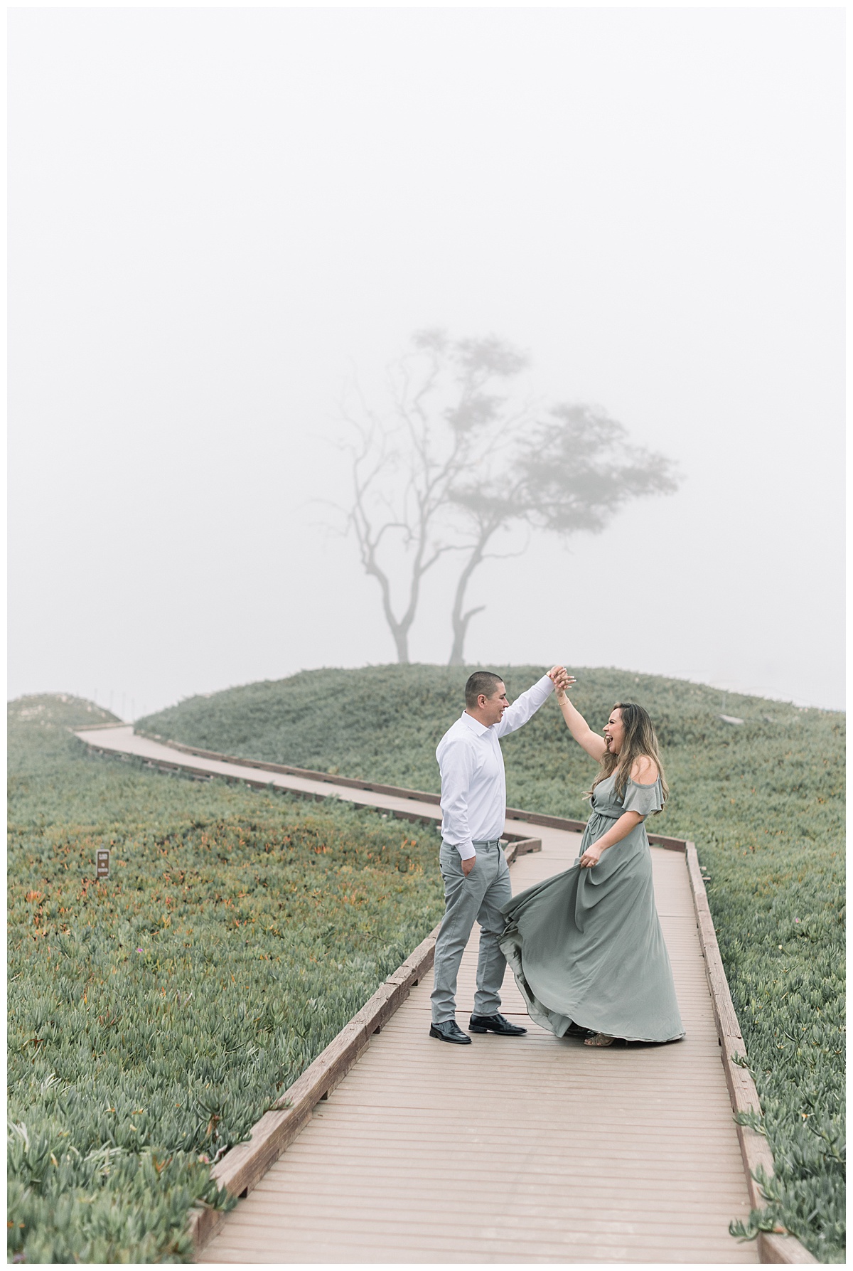 couple dancing on boardwalk in front of misty background